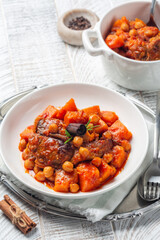 Pumpkin, lamb and chickpea stew with cinnamon sticks. Whie wood table, vertical image.