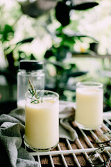 Corn juice smoothie on white rack placed on wood and plant backdrop in home garden pots. vertical photo