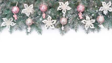 Fototapeta na wymiar Christmas background with a garland of spruce branches and glitter balls in pink and champagne colors. Christmas banner in cold pastel colors on a white background with copy space.