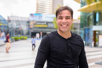 Portrait of handsome Persian man outdoors in city during summer