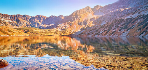 Autumnal Tatra mountains. Crystal water in the lake Big Pond surrounded by mountains in the Valley...