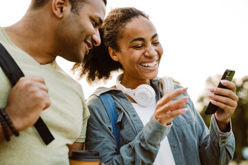 Multiracial young students smiling while using mobile phone