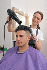 Professional hairdresser drying client's hair in salon