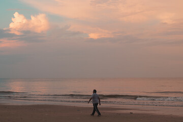 Naklejka premium person walking on the beach at sunset