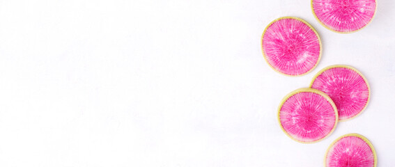 Web banner with watermelon radish slices on white with copy space. Colorful vegetable. Top view