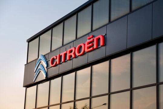 Minsk, Belarus. Oct 2021. Citroen sign on glass facade of dealership building, glowing logo in the evening. Citroen logo and sign on Citroen car dealer building. Citroen store, dealership shop