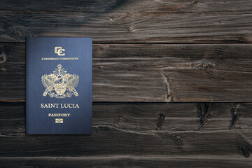 Saint Lucia passport on dark brown wooden board, sunlight