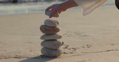Woman build zen stone tower with pebble stone