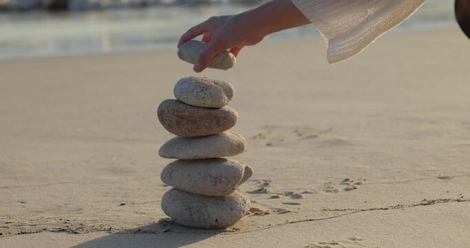 Woman build zen stone tower with pebble stone