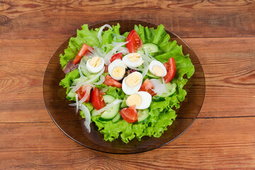 Vegetable salad with quail eggs on dish on rustic table