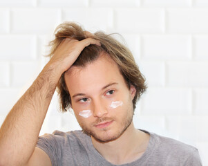 young man taking care of his undereye wrinkles applying facial mask. Applying the cream