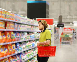 Man shopping in supermarket reading product information.(diapers,detergent)