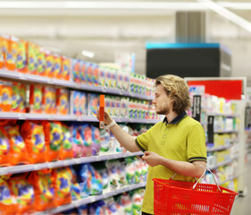 Man shopping in supermarket reading product information.(diapers,detergent)