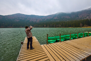 Tourist taking pictures of the landscape with St. Anne's Lake, Lake in Transylvania, Romania