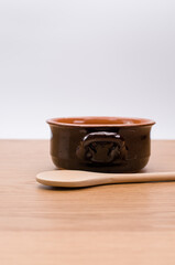 empty rustic terracotta kitchen bowl and spoon on a wooden tabletop with copy space