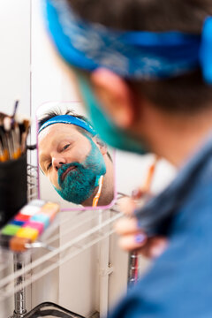 Man applying makeup on beard in dressing room