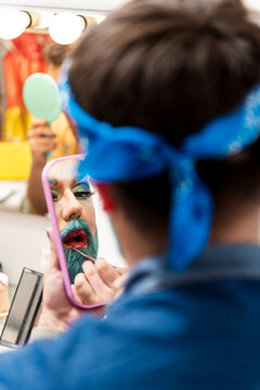 Bearded man doing drag queen makeup in dressing room