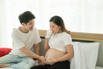 Asian man take care pregnant woman and drinking milk