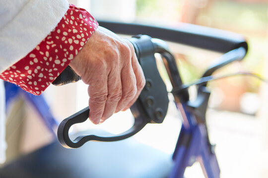 Seniorin mit H&auml;nden am Rollator Griff zu Hause