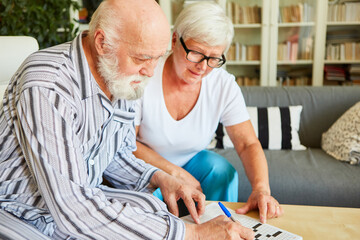 Altenpflegerin hilft Senior beim Kreuzworträtsel lösen
