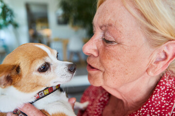 Glückliche Seniorin kuschelt mit ihrem kleinen Terrier