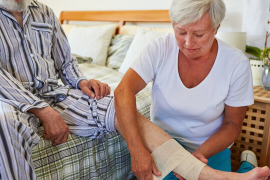 Altenpflegerin hilft Senior beim Verband anlegen