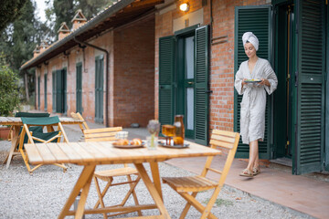 Fototapeta premium Woman carrying food to table for breakfast during resting in hotel at morning time. Concept of weekend, tourism and vacation. Young caucasian woman wearing bathrobe and wrapped bath towel on head