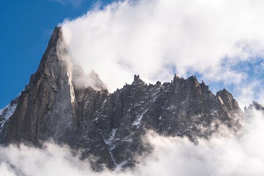 Aiguille du Dru mountain surrounded with clouds on sunny day, Chamonix, France