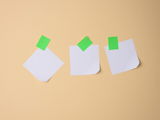 white square sheets of paper glued with green sticky paper on a light brown background