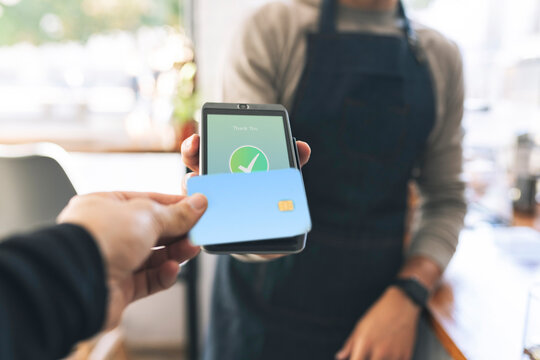 Cashier receiving payment through card reader in cafe