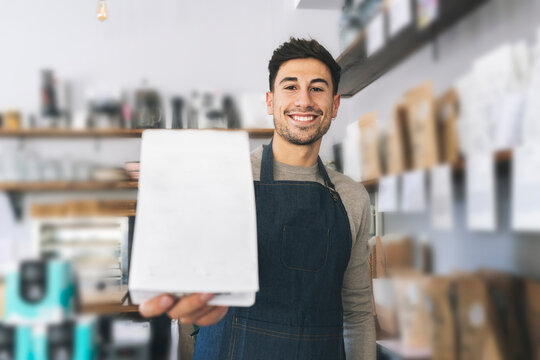 Smiling waiter holding credit card reader in cafe