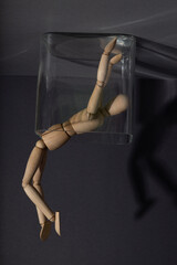 Wooden mannequin in a glass cube on gray background. loneliness, depression disorder concept. copy...