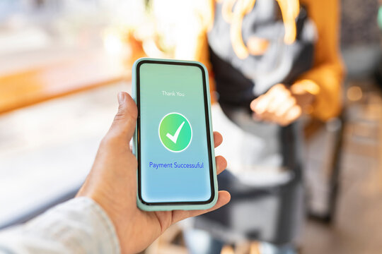 Customer with check mark paying through mobile phone in cafe
