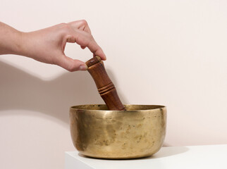 copper singing bowl and wooden clapper on a white table. Musical instrument for meditation,...