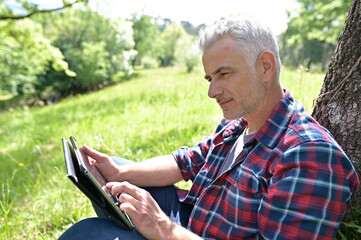 Obraz premium Man with grey hair and connected on digital tablet at home