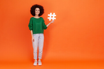 Full length portrait of woman with Afro hairstyle wearing green casual style sweater presenting...