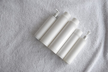 Bottles of professional natural cosmetics on the background of white towels.