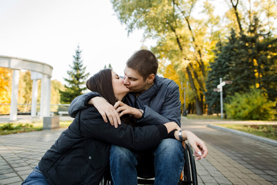 Boyfriend in wheelchair kissing girlfriend in park
