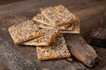 cereal cracker, rectangular bread or cookies with seeds and different seeds on a wooden background close-up