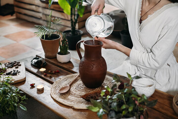 Pouring water into jug with cacao. Preparing ceremonial cocoa in atmospheric boho style cafe full...