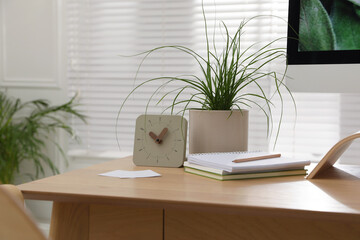 Fototapeta premium Notebooks, clock and houseplant on table in room