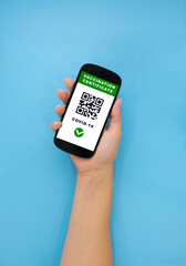 A woman's hand holds the phone, an electronic certificate of COVID-19 vaccination is on the phone screen.