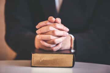 focus on woman's hand While praying for Christianity with blurry body background, casual woman prays with her hands with scriptures.