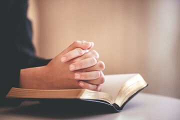 focus on woman's hand While praying for Christianity with blurry body background, casual woman prays with her hands with scriptures.