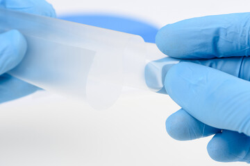 Scientist hold and bend flexible transparent thin film material in laboratory. Concept of research...