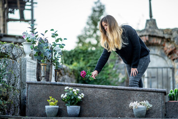 Blond woman putting flower on grave at cemetery