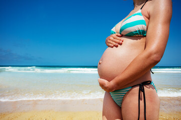 Close-up of pregnant woman's belly over the sea