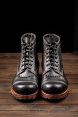 Hand crafted black leather high boots on wooden background