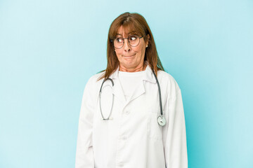 Middle age doctor woman isolated on pink background confused, feels doubtful and unsure.