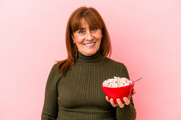 Middle age caucasian woman holding bowl of cereals isolated on pink background happy, smiling and cheerful.